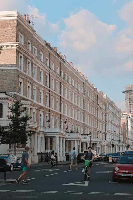 A wide view of a multi-storey Victorian-style residential building in North Kensington, featuring cream-colored stone facades, large sash windows, and decorative architectural details. In the foregrou