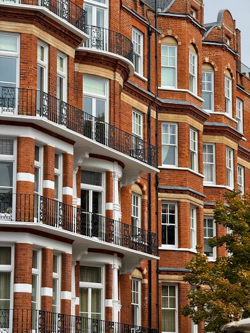 A wide view of a multi-storey Victorian-style residential building in North Kensington, featuring cream-colored stone facades, large sash windows, and decorative architectural details. In the foregrou
